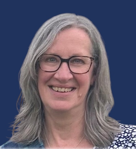 A colour image of a smiling person with shoulder length light coloured hair. They wear a blue and white patterned top and glasses. The image has a dark blue background.